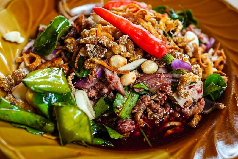 ลาบจานใหญ่โรยหอมเจียว พริกแห้ง และใบสมุนไพร